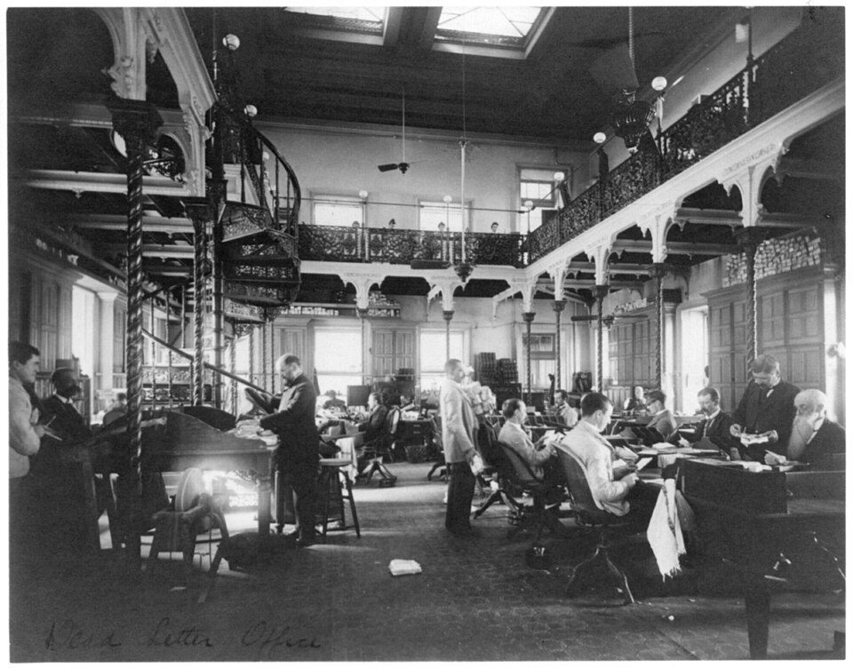 Historical illustration of clerks processing undeliverable mail at a 19th-century Post Office Dead Letter Office