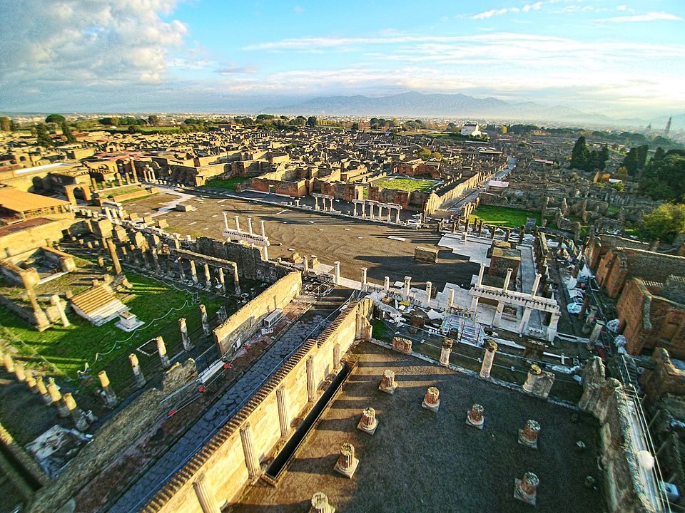 Pompeii Forum and Mount Vesuvius Pompeii archaeological site forum ruins with Mount Vesuvius looming in the background under blue sky in Campania, Italy