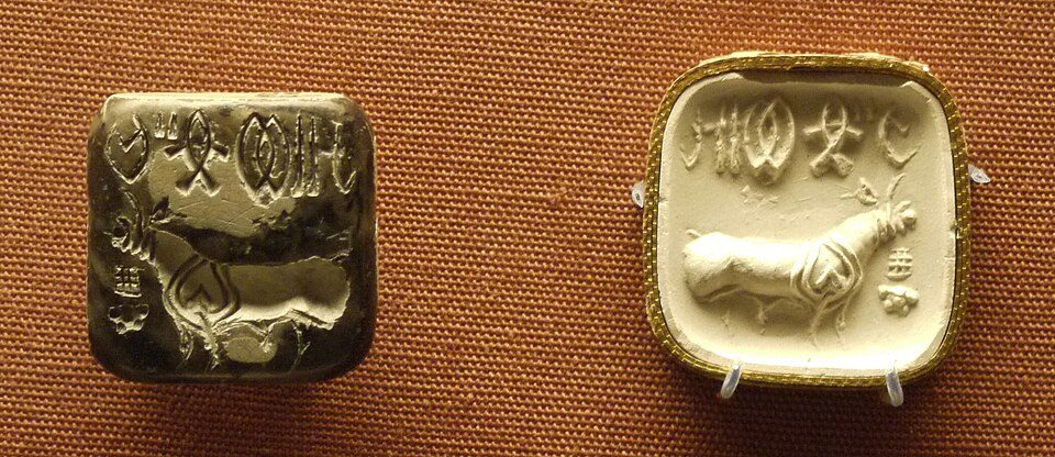 A carved steatite Indus Valley stamp seal showing a unicorn-like animal and undeciphered script