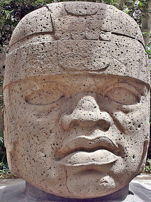 Massive carved basalt head with broad facial features and a fitted helmet-like headdress