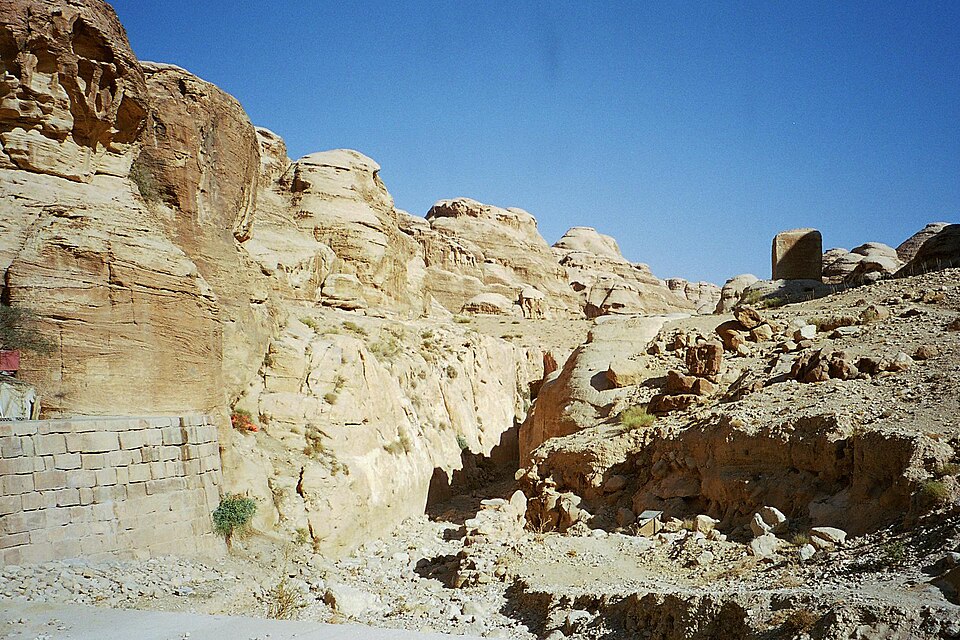 Ancient stone flood control dam blocking a narrow desert canyon.