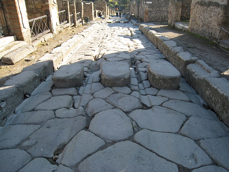 Deep grooves worn into the stone paving blocks of a Pompeian street.