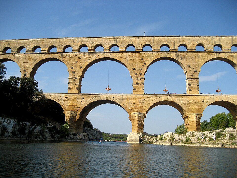 The Pont du Gard, a massive multi-tiered Roman aqueduct bridge spanning a river valley.