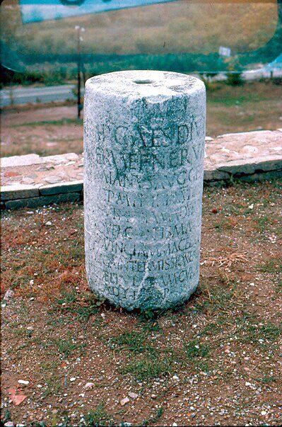 A cylindrical Roman stone milestone inscribed with a Latin dedication to Emperor Trajan