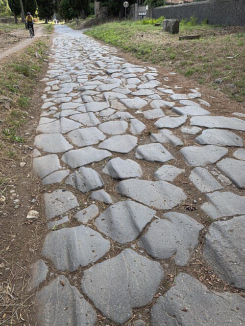 Polygonal basalt paving stones of the ancient Roman Via Appia, worn smooth and lined with cypress trees