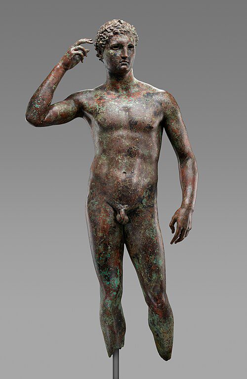 The Victorious Youth, a Greek bronze statue of a nude athlete crowning himself with an olive wreath, on display at the Getty Villa