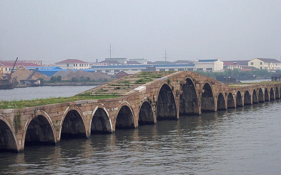 A long, low stone arch bridge spanning a wide canal.