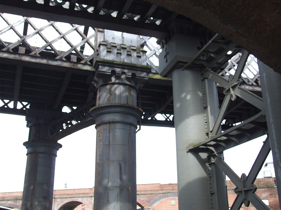 Historic brick warehouses and iron railway viaducts towering over a canal basin.