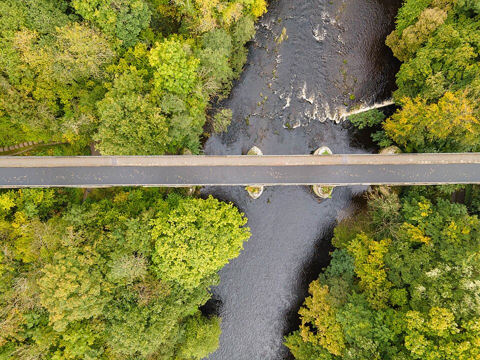 A towering aqueduct carrying a narrow ribbon of water atop slender stone pillars.